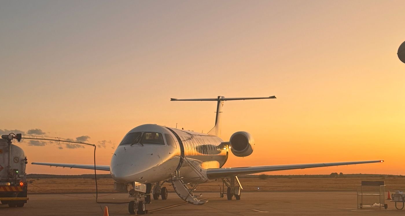 Business jet on the apron at sunset with airstairs down and a fuel bowser alongside