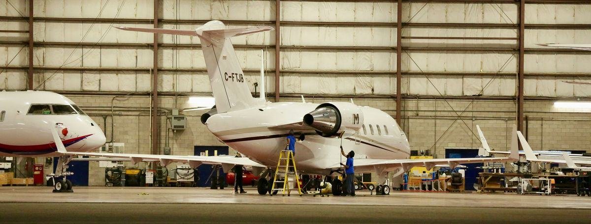 Engineers inspecting a business jet in a maintenance hangar during a pre-purchase inspection